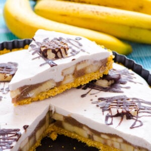 Healthy banana cream pie slice on top of pie and bananas nearby.