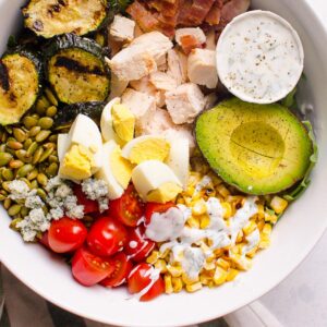 Healthy cobb salad in a bowl with chicken, corn, tomatoes, green and ranch dressing.