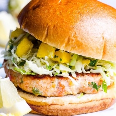 Healthy salmon burger on a bun with mango slaw.