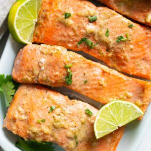 Lime ginger salmon garnished with cilantro and lime on a platter.