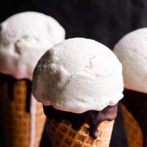 Three scoops of vegan vanilla ice cream in sugar cones.
