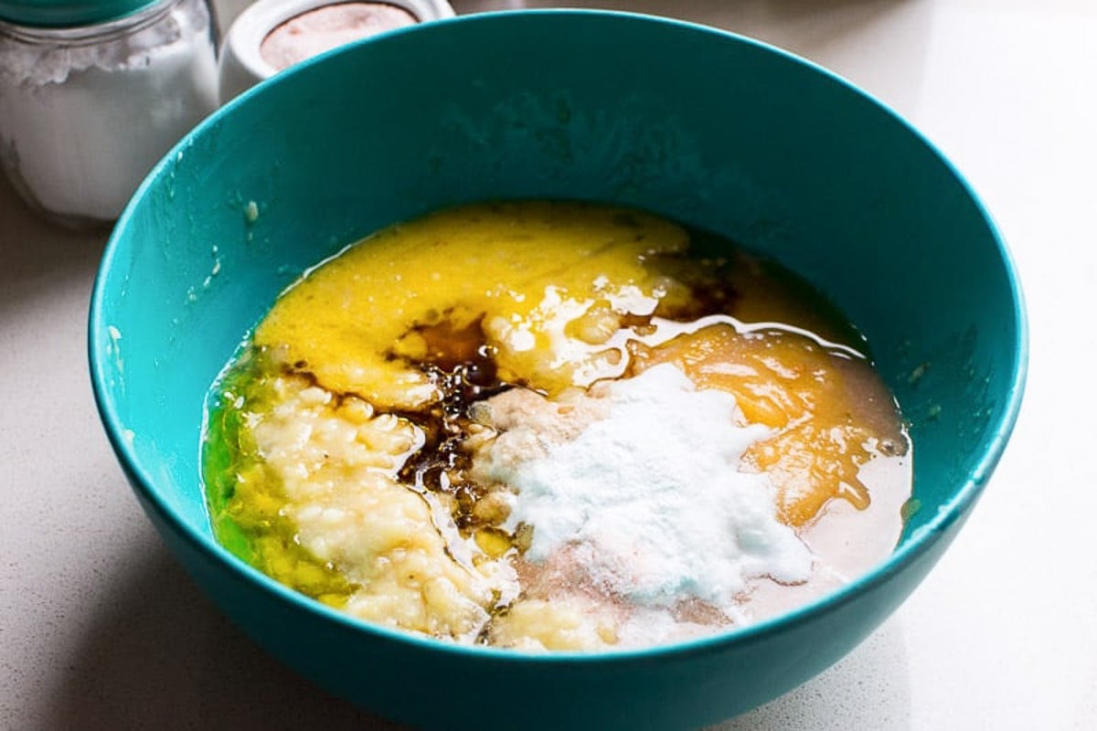 Eggs, applesauce, mashed banana, oil and baking staples in bowl.