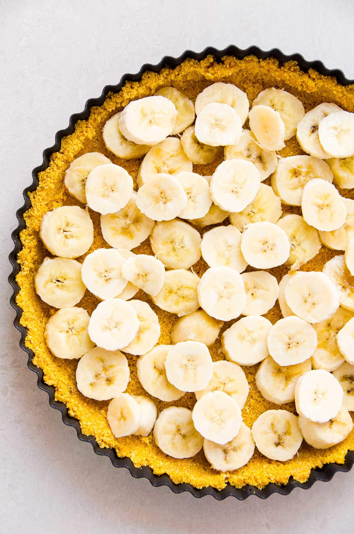 Sliced bananas layered over pie crust in a tart pan. 