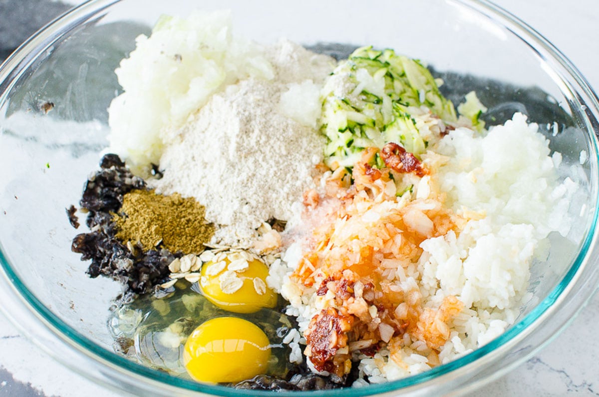 Black beans, rice, eggs, zucchini, flour and spices in a glass bowl.