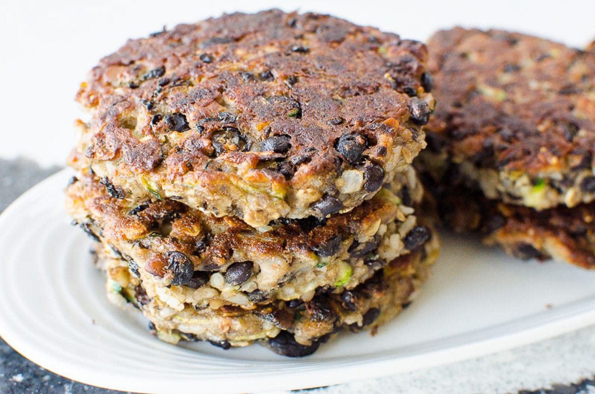 Healthy black bean burger patties stacked on a white plate. 