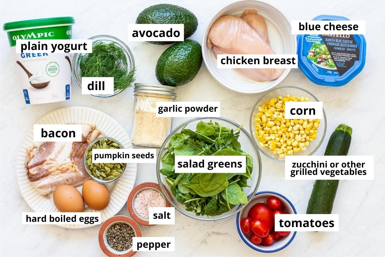 Salad greens, blue cheese, chicken, eggs, corn, bacon, tomato, zucchini, yogurt, pumpkin seeds, garlic powder, salt, pepper.