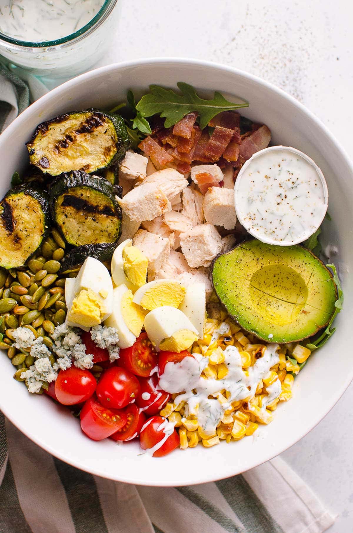 Healthy cobb salad with chicken in a bowl with healthy ranch dressing in jar.