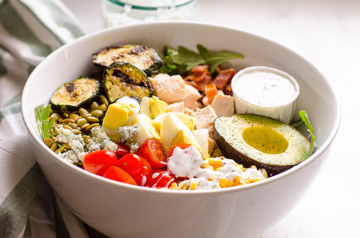 Healthy cobb salad with chicken, greens and vegetables in a salad bowl.