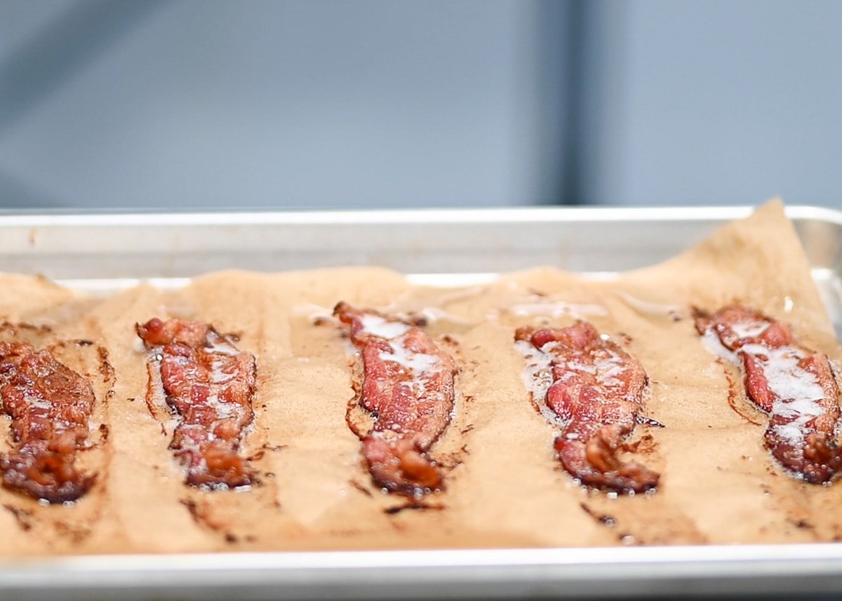 Baked bacon strips on lined with parchment paper baking sheet.