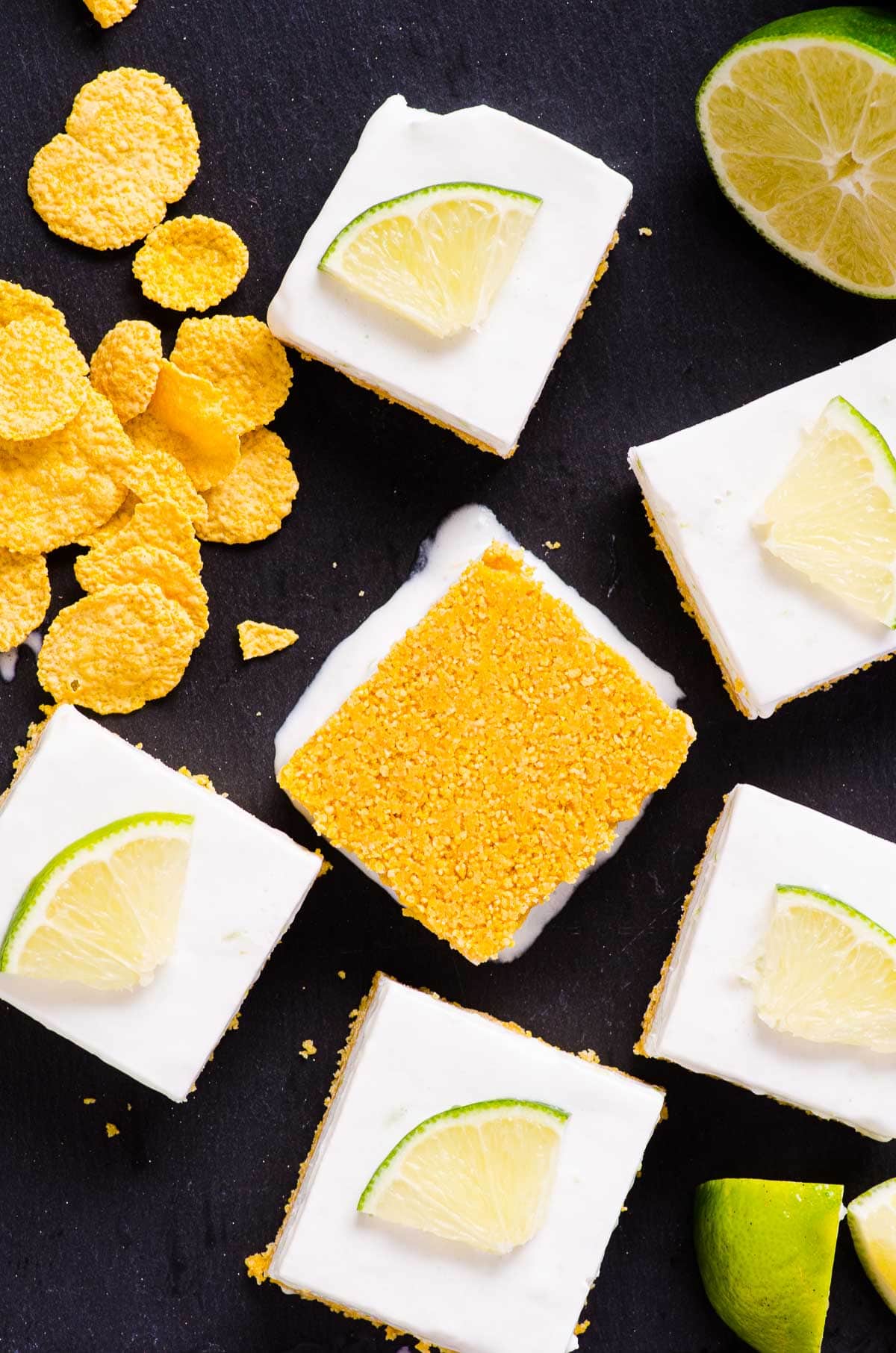 Healthy key lime pie bars with one square upside down and cornflakes.