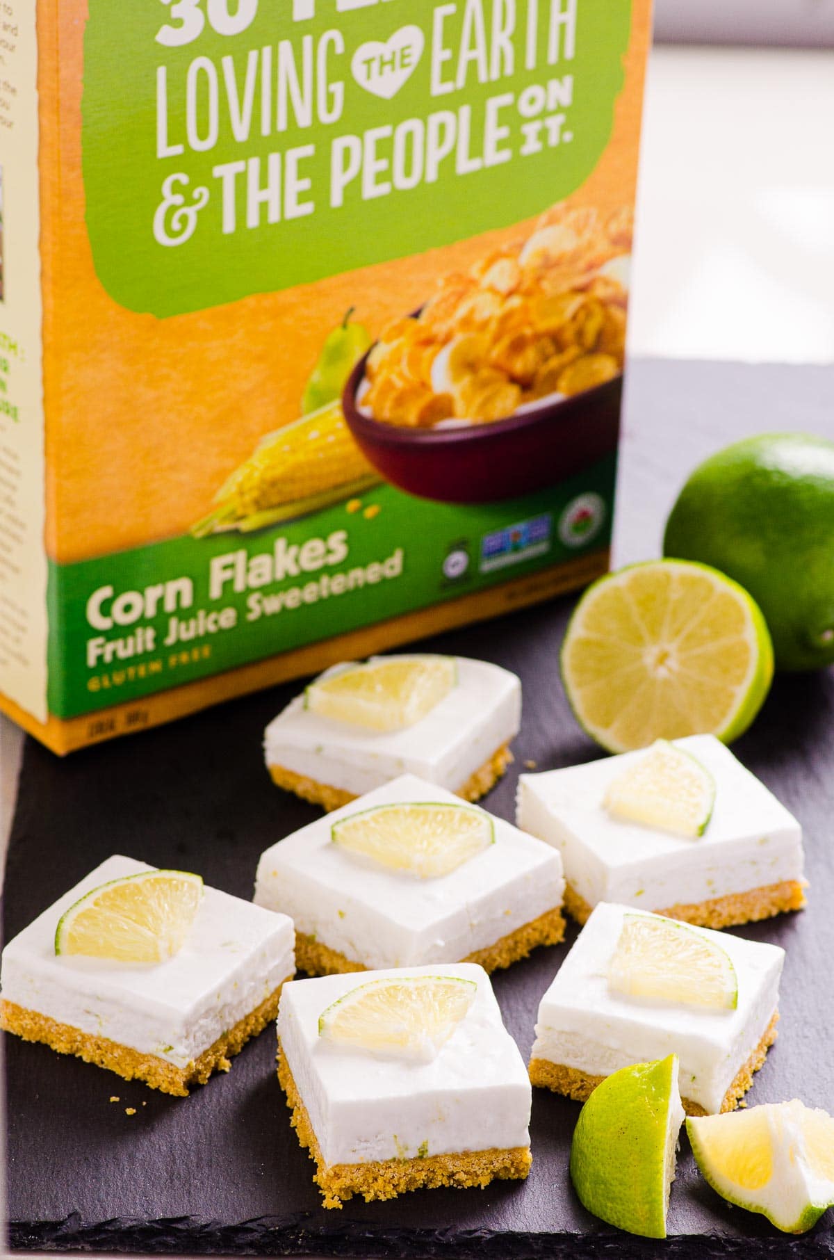 Healthy key lime pie bars with box of corn flakes and fresh lime.