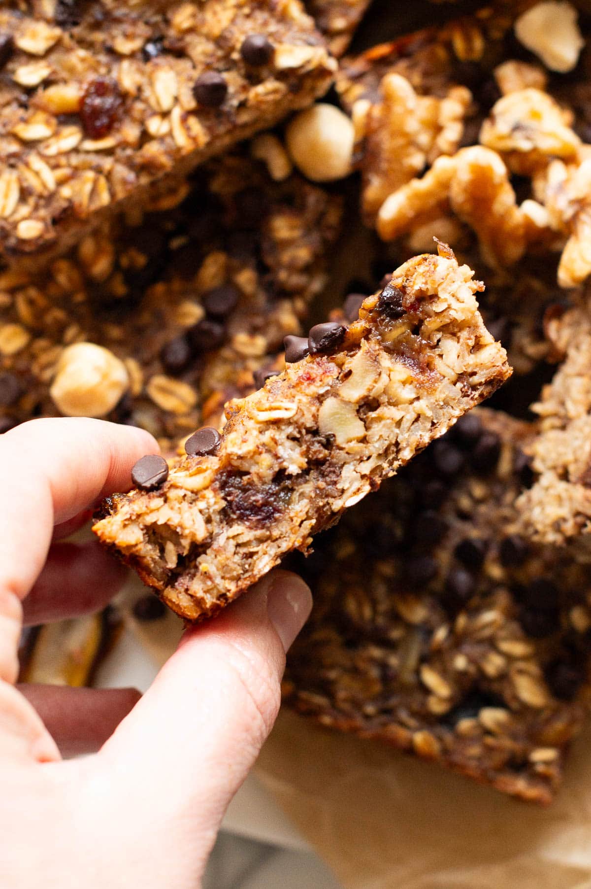 Person holding an oatmeal bar showing texture inside.