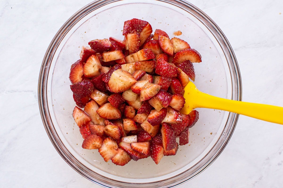 Strawberries in a bowl with yellow spatula.