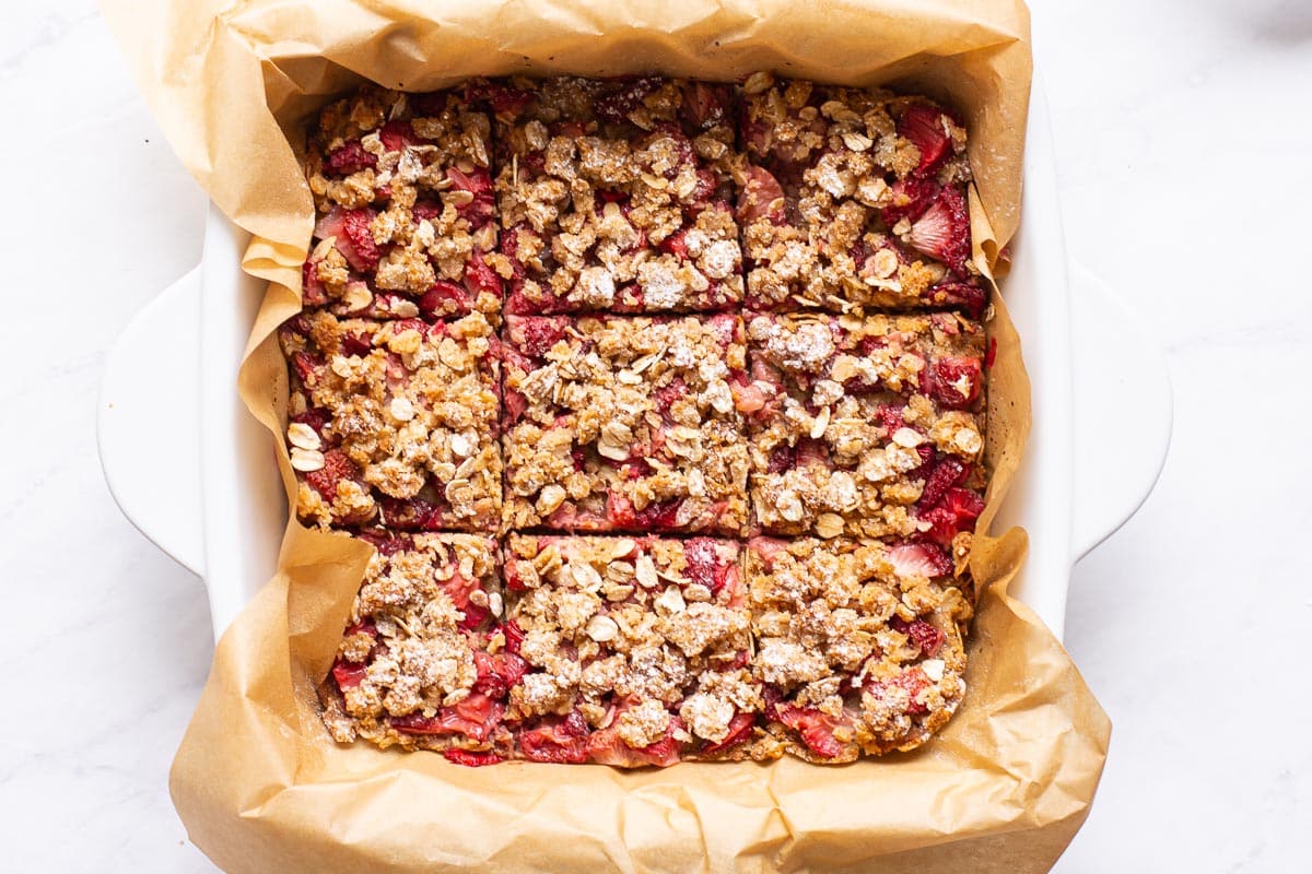 Healthy strawberry oatmeal bars in a parchment lined pan cut into 9 squares.