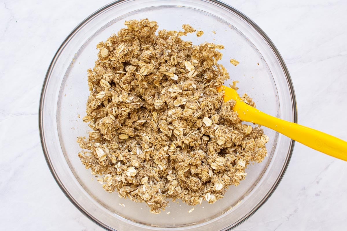 Mixing oats, almond flour, sugar, cinnamon, butter, maple syrup and vanilla in a bowl. 