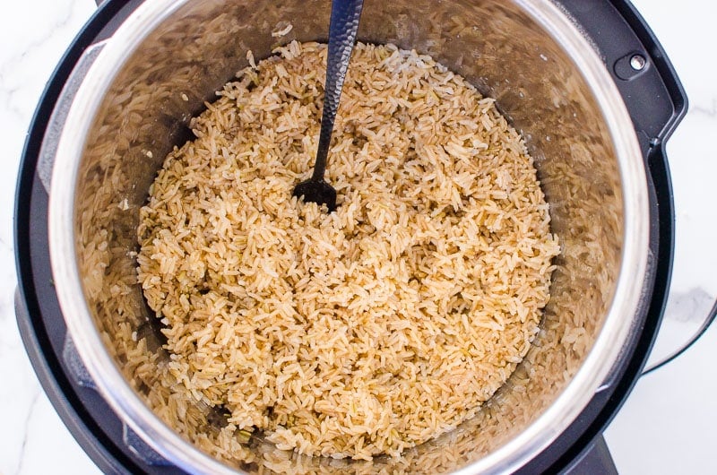 Cooked brown rice inside Instant Pot with a fork.