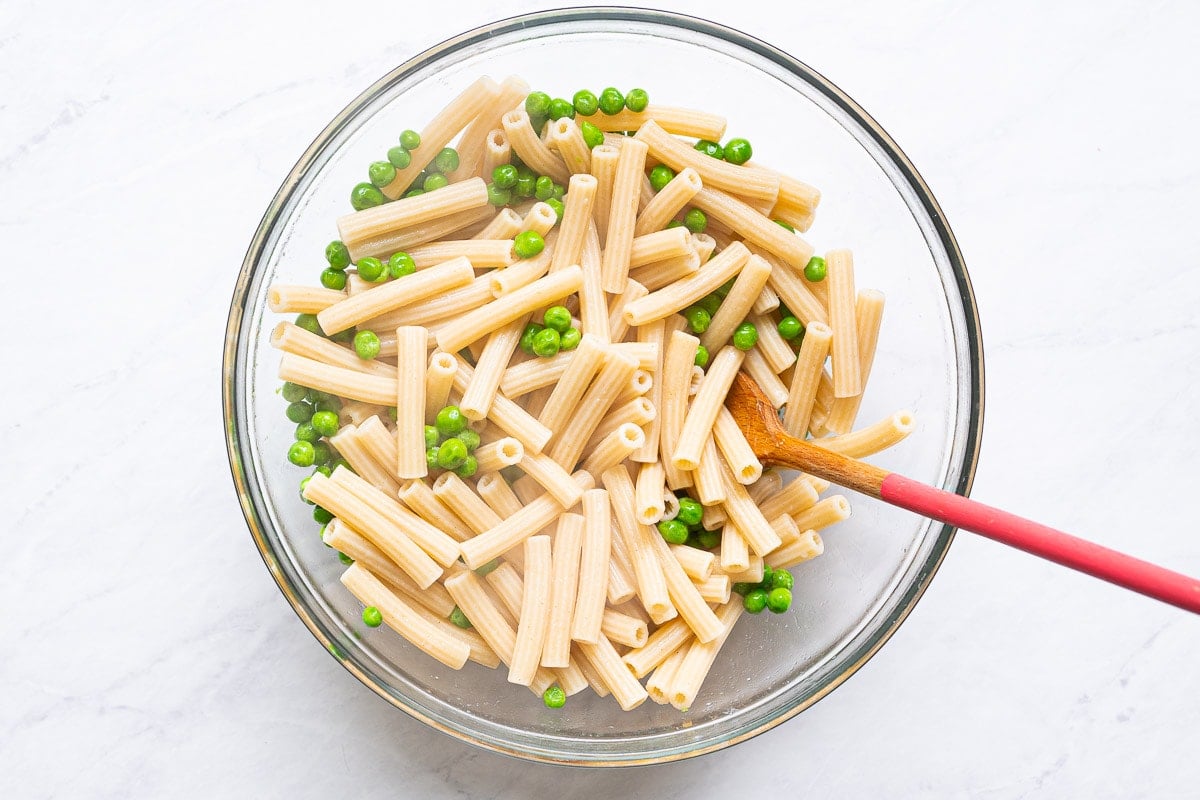 Cooked pasta in a bowl with sweet peas.