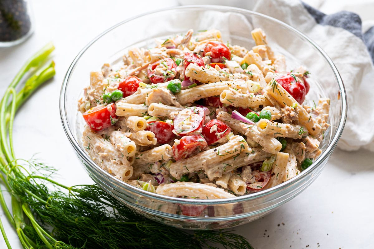 Pasta with tuna in a bowl with dill and a linen.