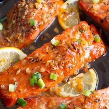 A few honey garlic glazed salmon filets with lemon and green onion garnish.