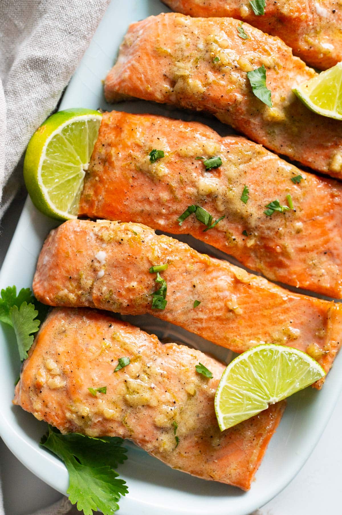 Lime ginger salmon garnished with cilantro and lime on a platter.