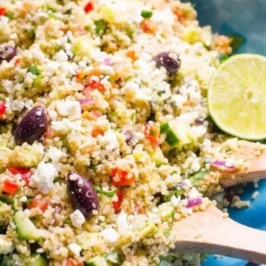 Mediterranean quinoa salad in a blue bowl with lime.