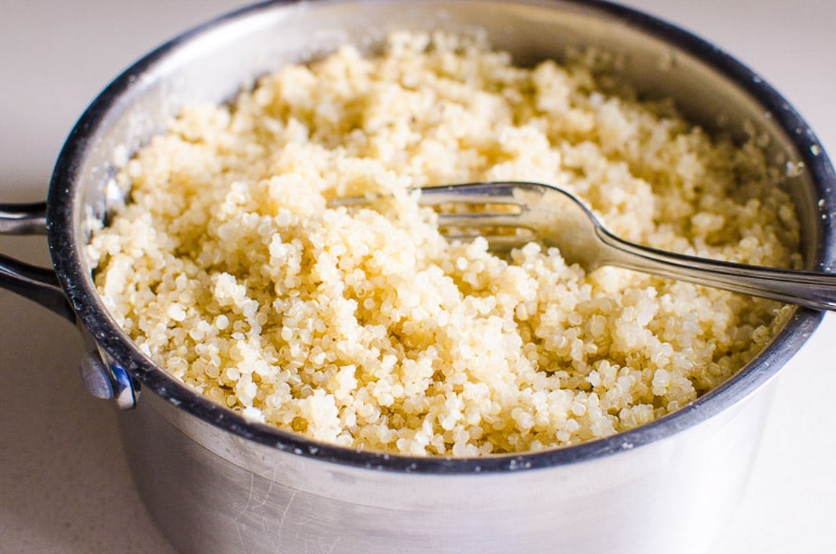 Cooked quinoa with a fork in a pot.