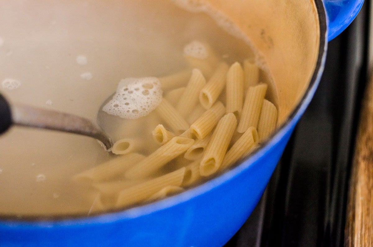 Pasta cooking in water in blue pot.
