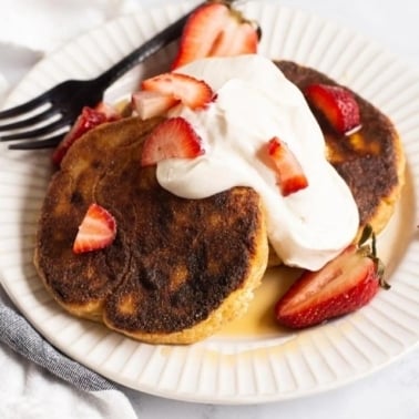 Ukrainian syrniki with sour cream and fresh strawberries.