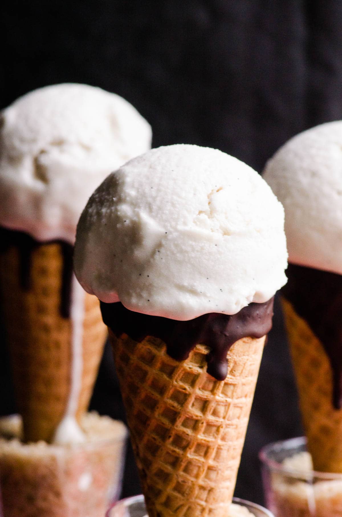 Three scoops of vegan vanilla ice cream in sugar cones.