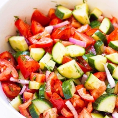 Cucumber tomato salad in a white bowl.