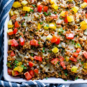 Ground turkey quinoa casserole garnished with red and yellow tomatoes in white dish.