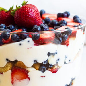 Healthy trifle layered with pudding, sliced angel food cake and berries in a glass trifle bowl.