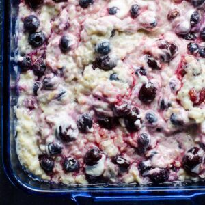 Healthy brown rice pudding with cherries in blue baking dish.