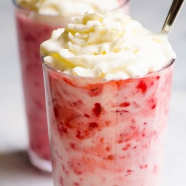 Strawberry yogurt topped with whipped cream in a glass.