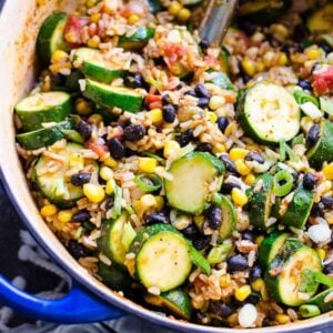 Tex mex rice, beans, corn and zucchini in blue pot with green onions.
