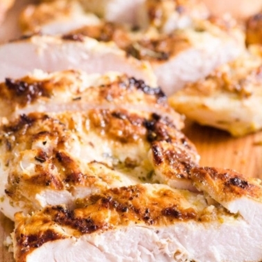 Sliced grilled chicken breast on cutting board.