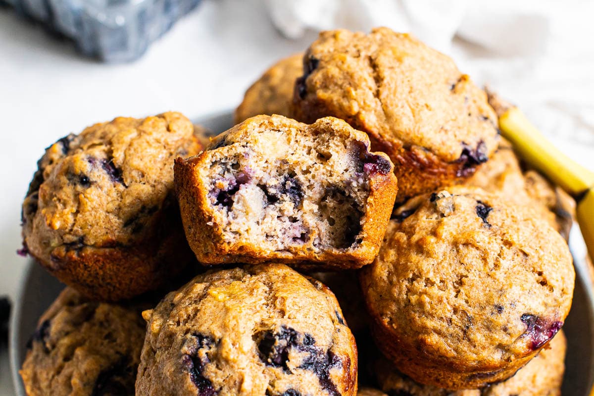 Muffins stacked in a pile with one muffin missing a bite.