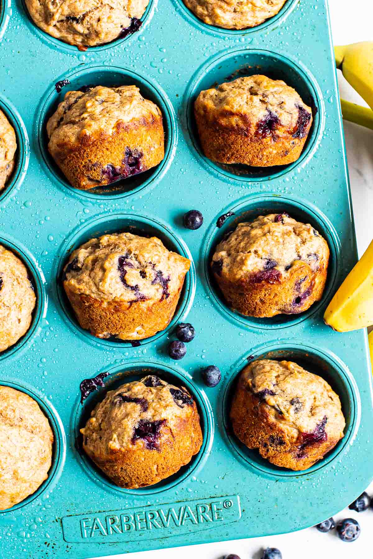 Healthy banana blueberry muffins on a side in a muffin tin.