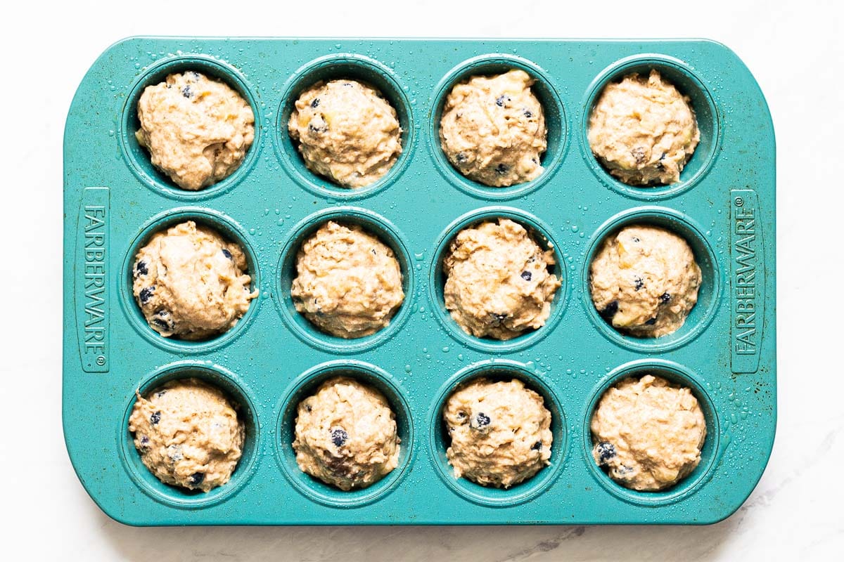 Raw muffin batter in a blue muffin tin. 