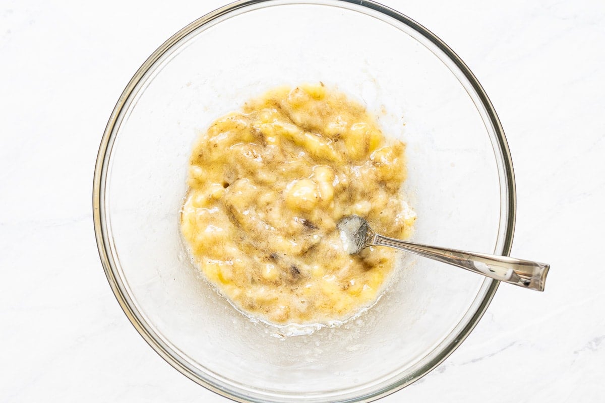 Mashed bananas in a bowl with a fork.