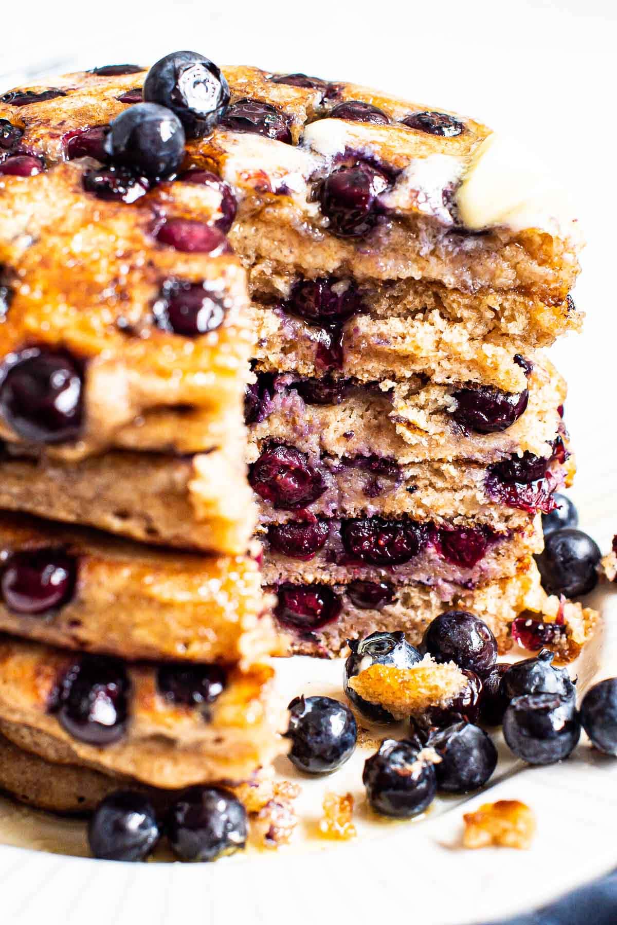 A stack of healthy blueberry pancakes cut and showing texture inside.