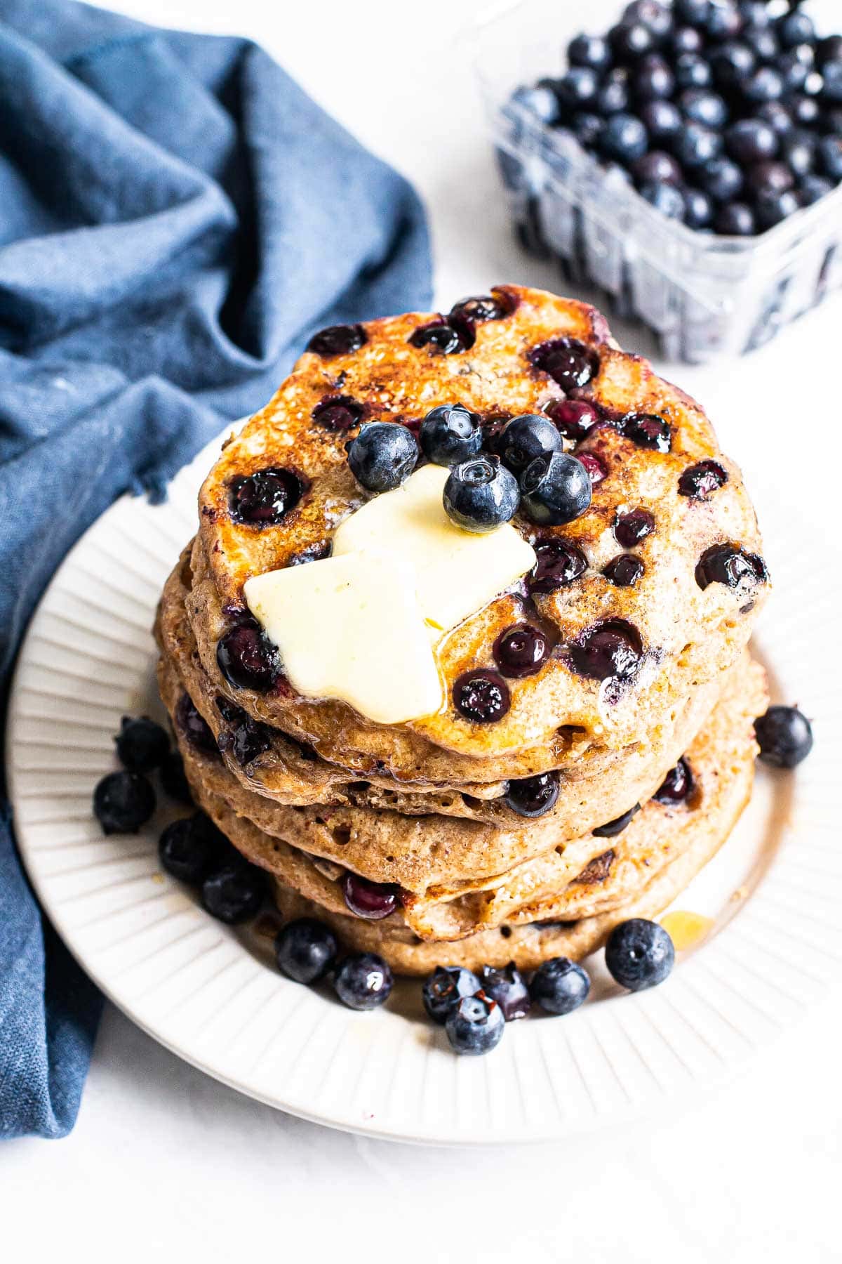 Above photo of a stack of homemade blueberry pancakes topped with butter.