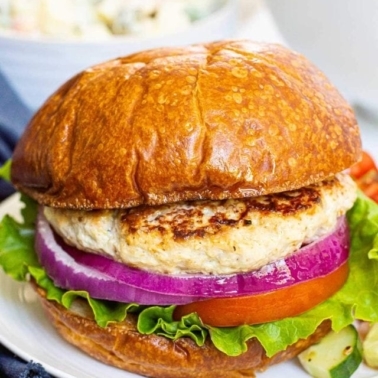 Healthy ground chicken burgers on a bun with lettuce, tomato and onion.