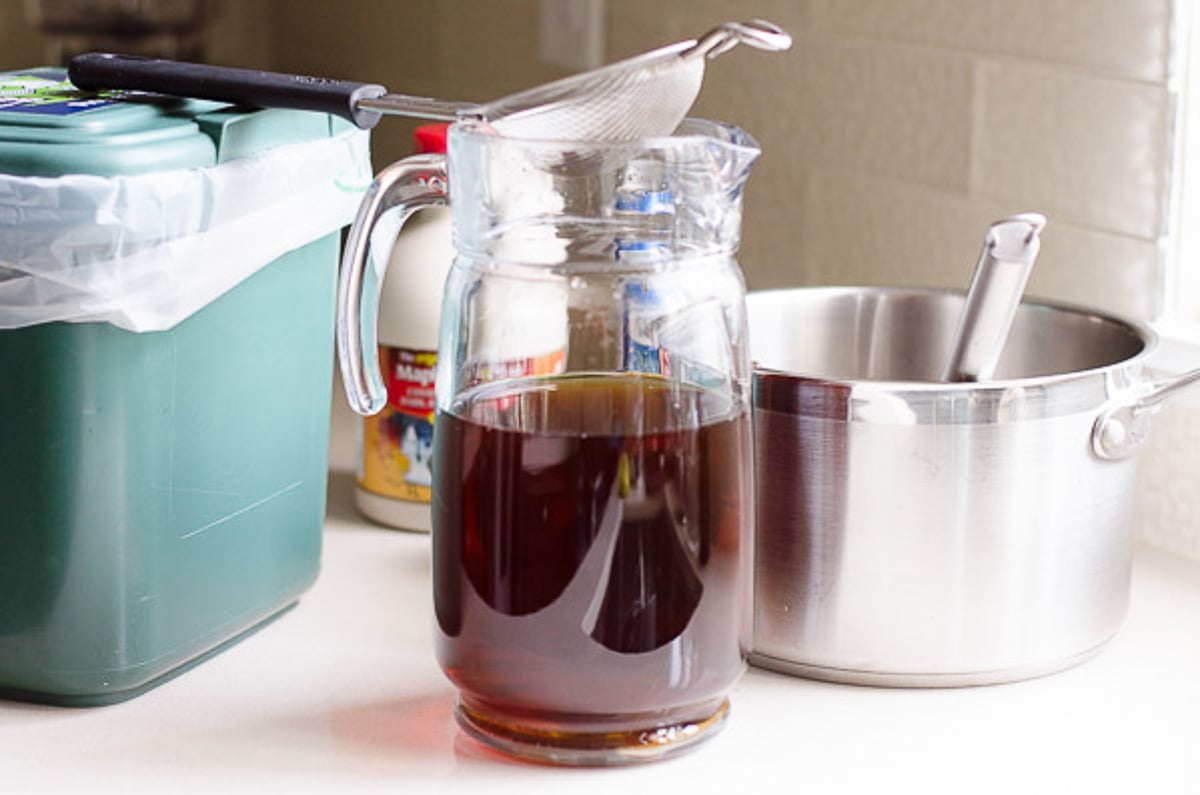 Cooled brewed tea in pitcher with mesh sieve on top.