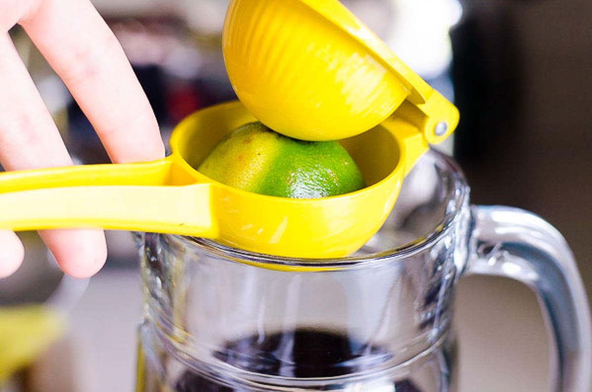 Squeezing lime over pitcher of brewed tea.