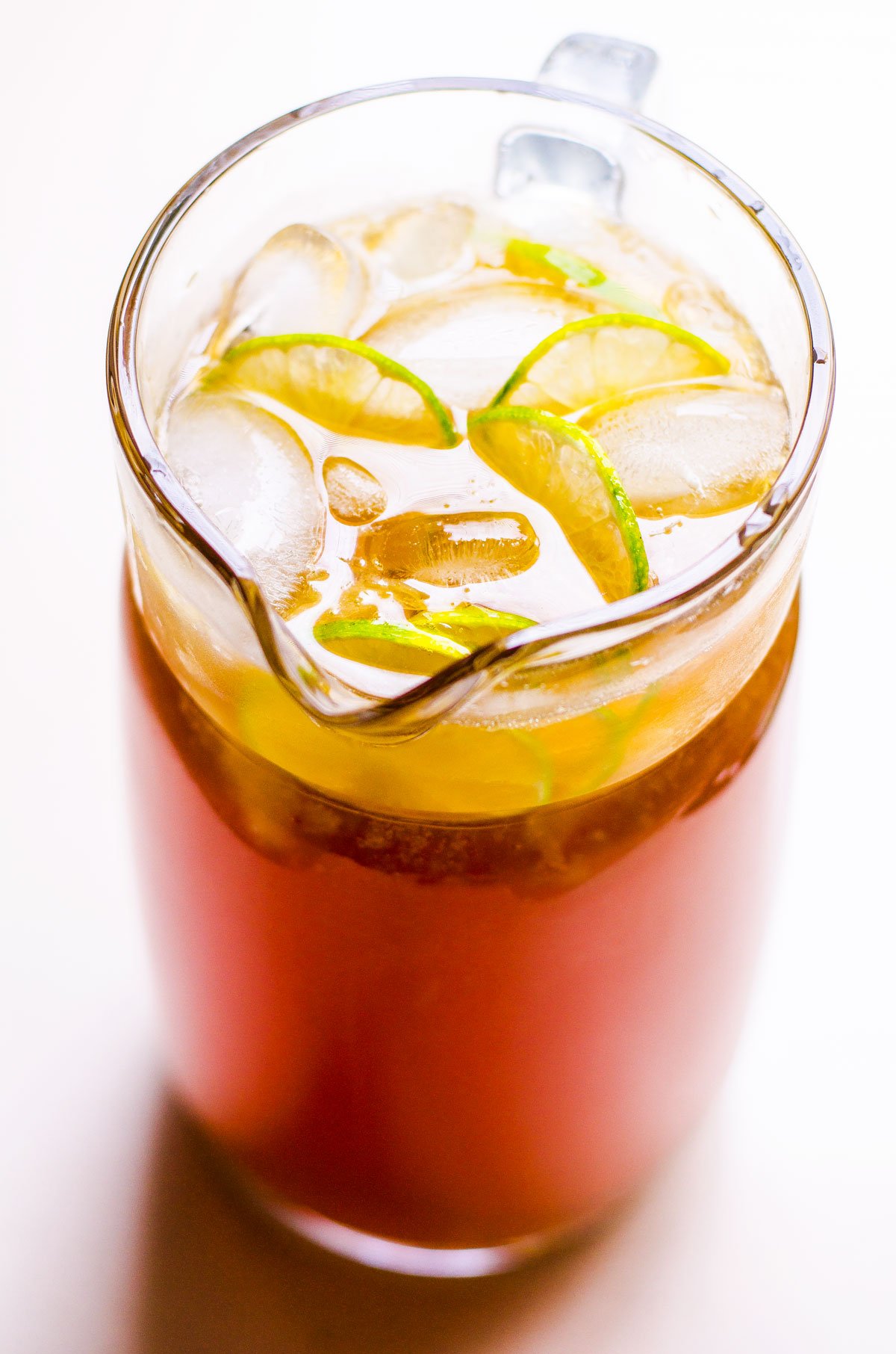 Healthy iced tea in a pitcher with ice and slices of lime.