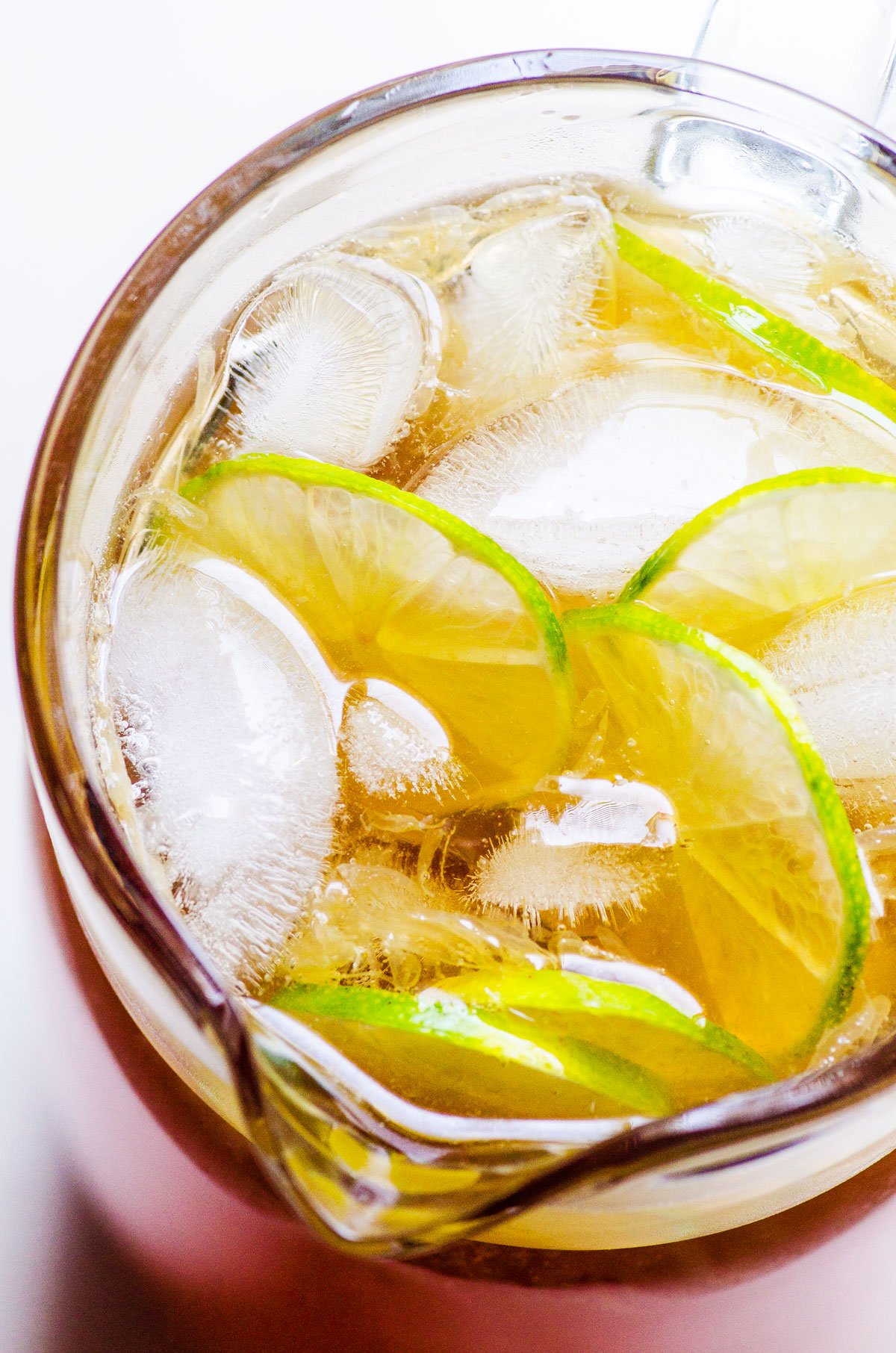 Healthy iced tea in a pitcher with lime slices and ice cubes.