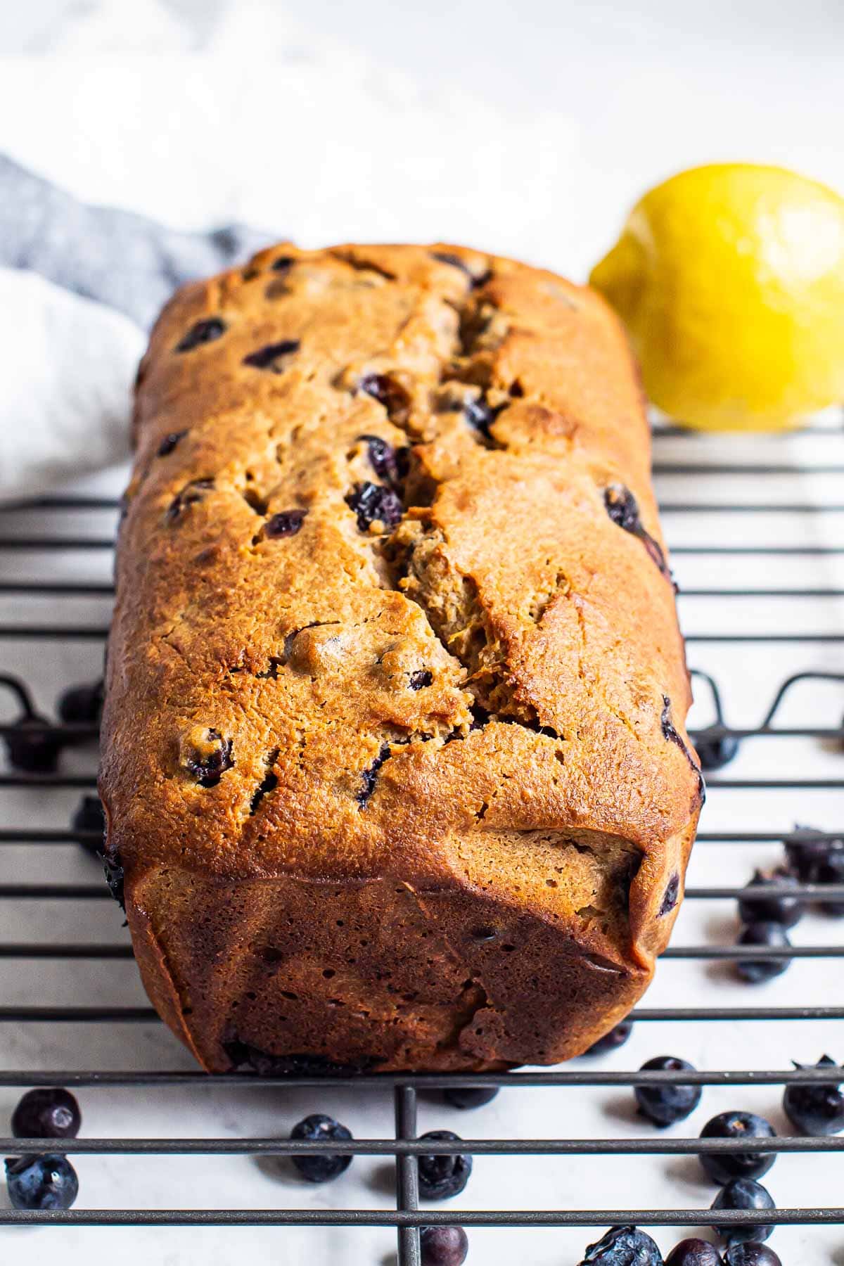 Healthy blueberry bread on bakers rack with fresh blueberries.