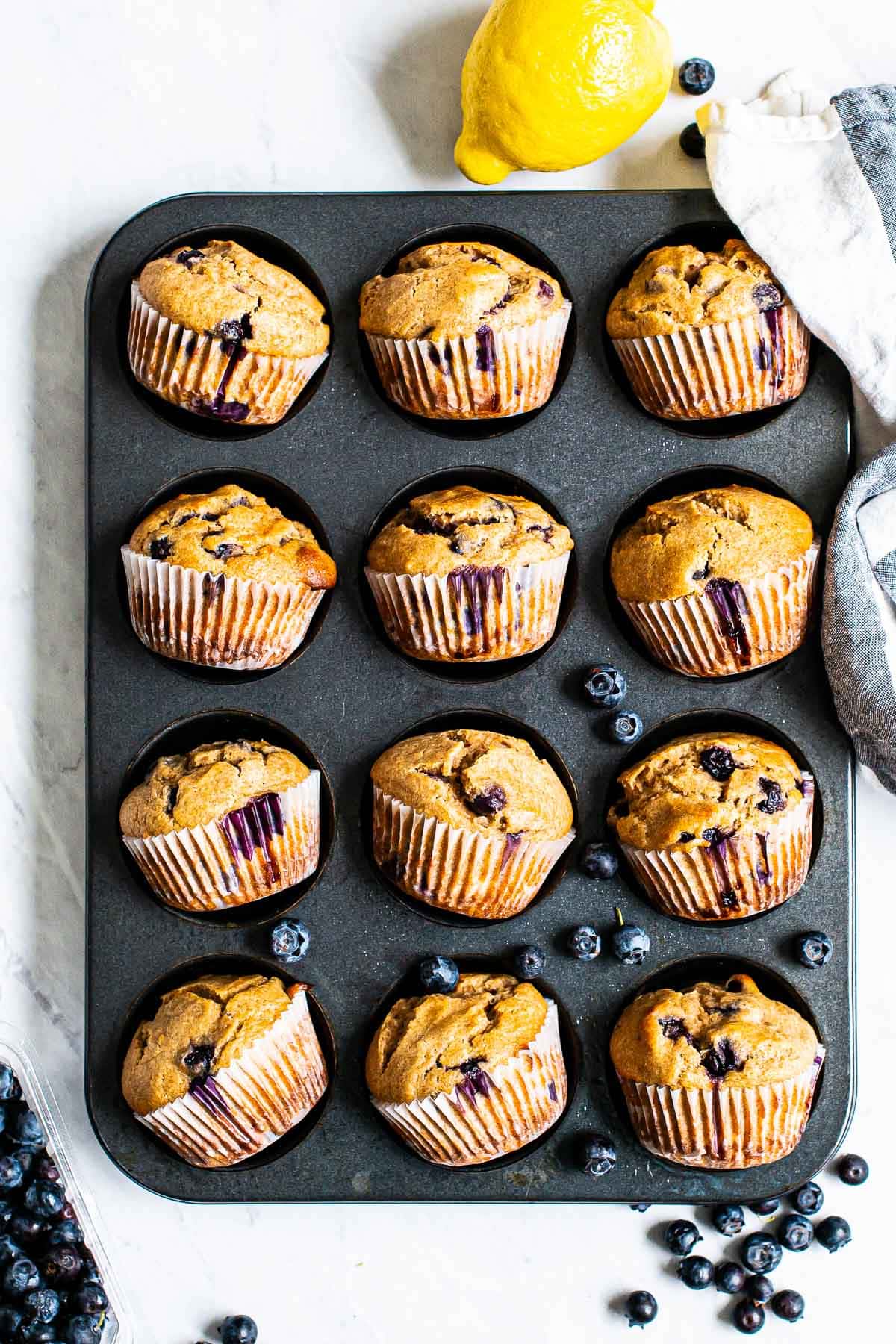 A muffin tin of healthy lemon blueberry muffins on their sides.