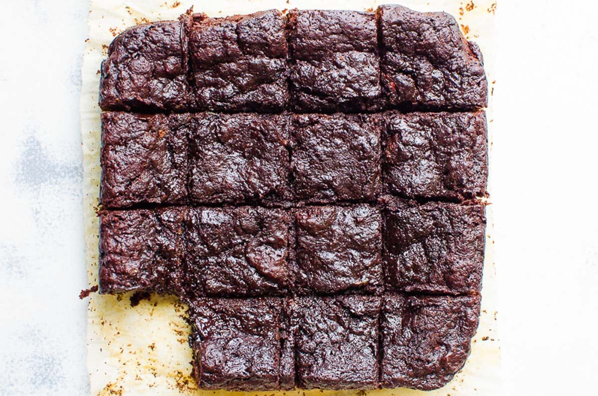 Health zucchini brownies cut into squares on counter with one browning missing.